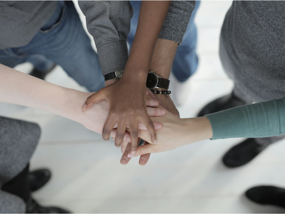 Several people stack hands together as viewed from above.